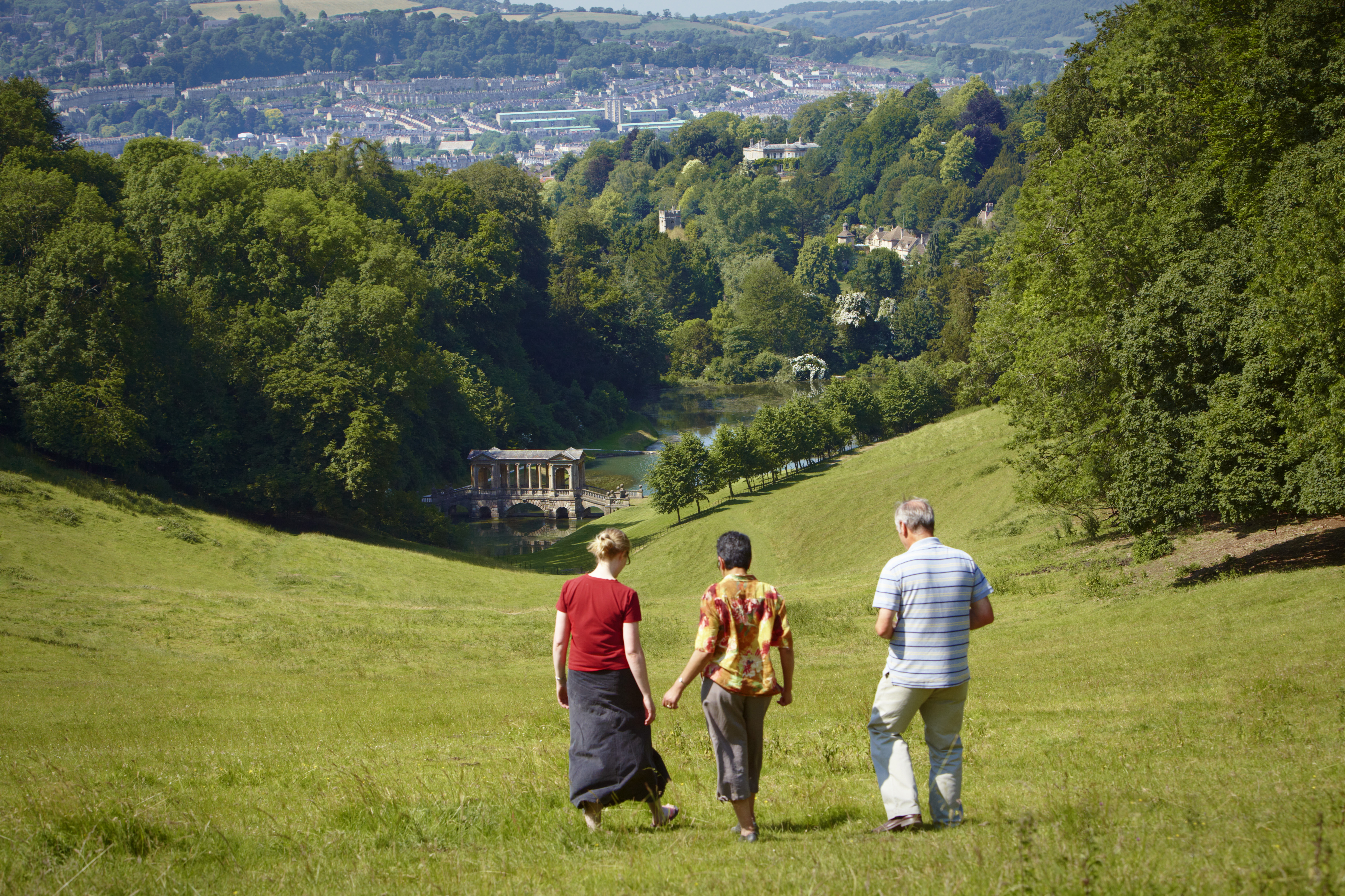 three people walking down a hill overlooking bath